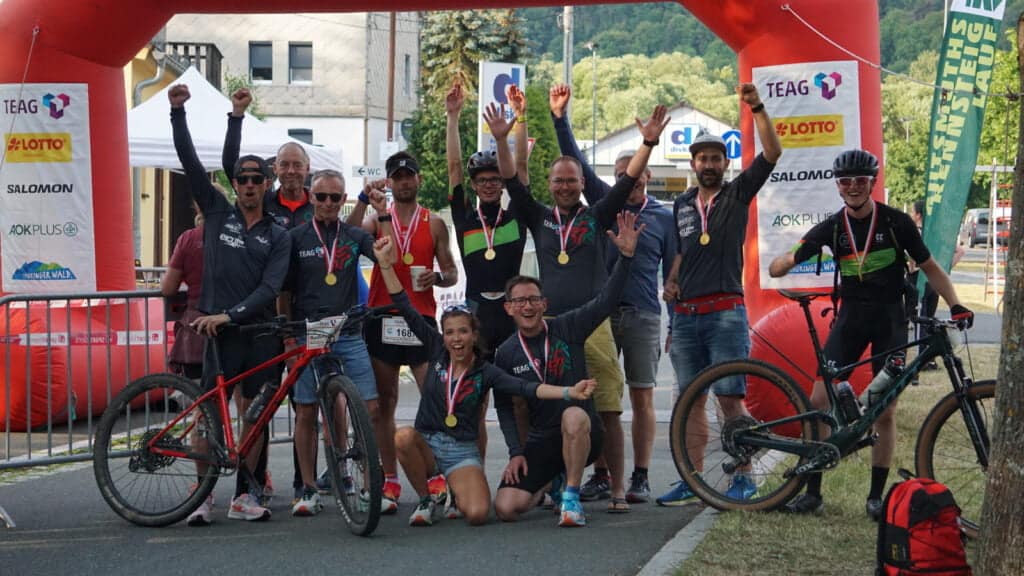 Gruppe Männer und eine Frau im Ziel mit Medaillen