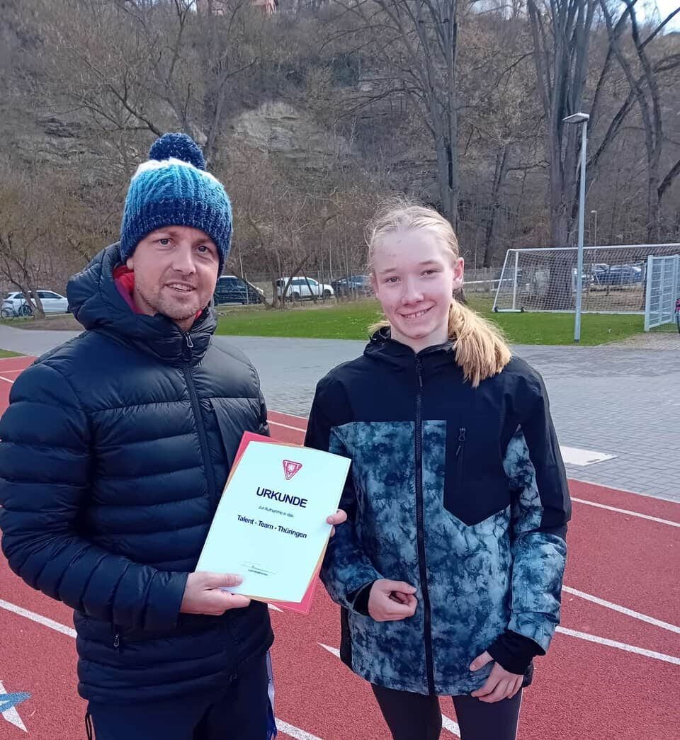 Trainer übergibt Urkunde an Athletin